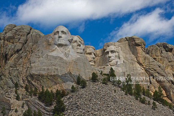 Mount Rushmore with cumulous clouds in a blue sky
